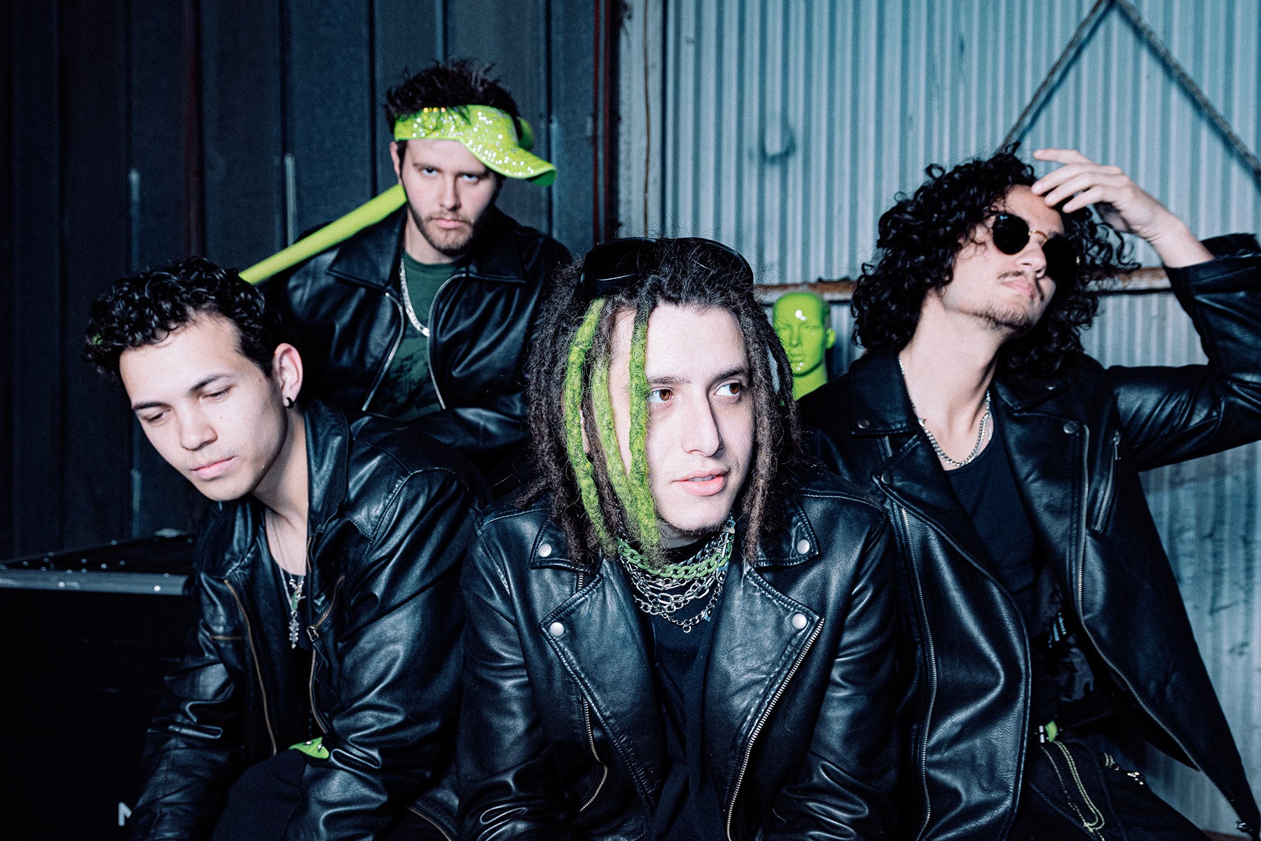 Four individuals in leather jackets with green accents in a casual setting.